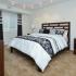 Spacious master bedroom with plush carpet furnished with dark wood and black and white linens