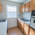 Kitchen with a vintage stovetop, oven, and large window at Evergreen Club apartments for rent