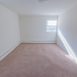 A plush carpeted bedroom with two windows and baseboard heating at Evergreen Club apartments for rent