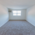 Living room with air conditioning unit and plush carpeting at Evergreen Club apartments for rent in Broomall, PA