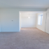 Spacious living area into dining room with white walls and carpeting