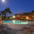 Palms of Monterrey, exterior, night, sparkling blue swimming pool, lounge chairs, clubhouse, palm trees