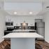 The Maxwell - Kitchen with White Granite Countertops, Stainless Steel Appliances, White Cabinets, and Dark Wood-Style Flooring