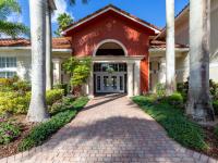 Cobblestone driveway and exterior of main building and leasing lobby, landscaped with palm trees