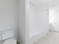 Nely renovated large bathroom with toilet, shower tub, linen closet, and sink with cabinets