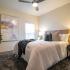 Pet Friendly Apartments in West Nashville TN - Summit at Nashville West - Bedroom with Plush Carpet, Large Bed, Nightstand with Lamp, Window, and a Ceiling Fan.