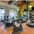 View of carpeted fitness center with exposed beam ceiling, treadmills, ellipticals, stationary bikes and circuit training equipment arranged throughout room