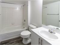 Bathroom with shower tub, toilet, sink with cabinets, and hardwood flooring