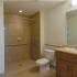 Bathroom with handicap accessible shower, toilet, sink with cabinet, mirror, and shelving