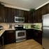 Modern kitchen with dark wood cabinetry and granite countertops and stainless steel appliances
