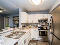 kitchen with stainless steel fridge and stove and white cabinets and breakfast bar at the cove
