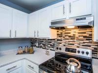 kitchen with stainless steel stove and white shaker cabinets at the cove apartments