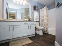 full bath with tub and vinyl wood like flooring and large vanity at the cove apartments