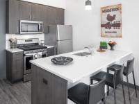 kitchen with breakfast bar quartz counters and stainless steel appliances at parallax apartments