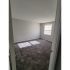 Carpeted room with gray walls and a square window bringing in natural light.