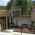 Marcell Gardens Apartments, Rental office, Flower beds, palm tree, Shady area with bench.