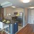 Arabella 101, interior, front entrance, kitchen, open concept, breakfast bar counter, stainless steel appliances, tile and wood floor, refrigerator, microwave, gas stove/oven, wine rack, white chairs