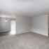 Spacious carpeted living space with view into dining area and patio entrance, lots of natural lighting