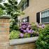 Exterior of residential building with blooming flowers and green bushes at Sterling Glen apartments for rent