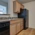 Coryell Crossing Apartments kitchen with black appliances and hardwood style flooring