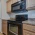 Coryell Crossing Apartments kitchen with black appliances and wood cabinets