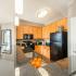 Fully-equipped kitchen with island, pendant lighting, granite countertops, and modern black appliances