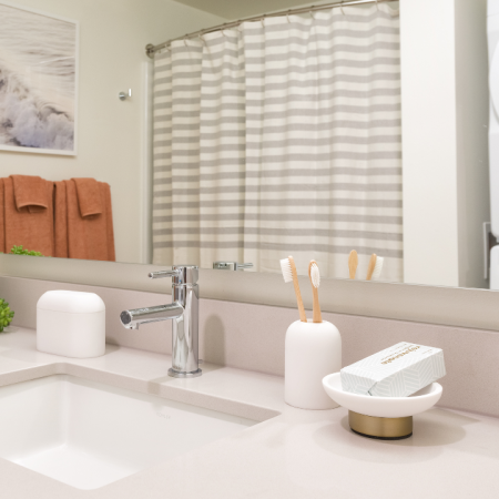 Bathroom with deep sinks, quartz countertops and full sized washer and dryer at Modera Broadway Apartments.
