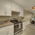 Remodeled 2 bedroom open layout with white cabinets, stainless steel oven, and partially furnished living/dining room