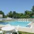 Community swimming pool with umbrellas and lounge chairs at Naamans Village Apartments in Claymont, DE.