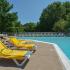 Community swimming pool has lounge chairs and umbrellas spread out on the sundeck at Summit Trace Apartments in Langhorne, PA.