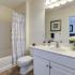 Bright white bathroom with white vanity and built-in linen closet. Oversized mirror hung above vanity with toilet and shower to the left at Summit Place apartments in Methuen, MA.