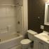 Homeroom Lofts Apartments, interior, bathroom, tiled floor, brick wall, shower/tub, toilet, sink, cabinets, mirror